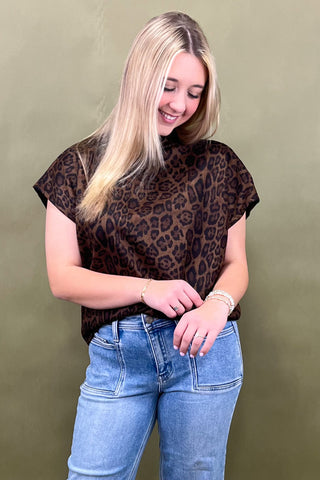 Woman wearing a leopard print top and blue jeans against a green background