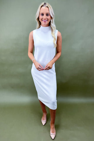 Woman wearing a white sleeveless dress against a green background