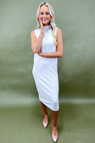 Woman wearing a white sleeveless dress against a green background