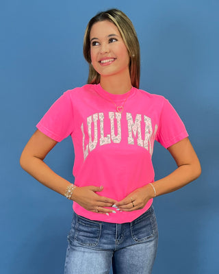 a bright pink short-sleeve t-shirt with 'LULU MAC' printed in white camo arched letters across the chest