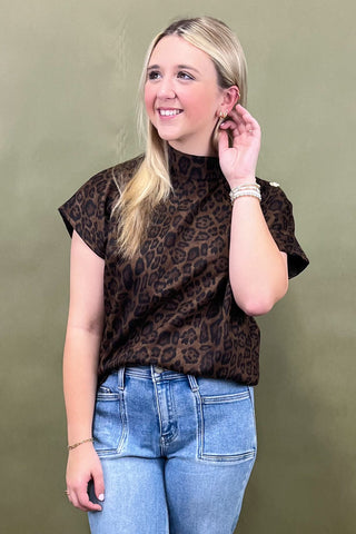Woman wearing a leopard print top and blue jeans against a green background