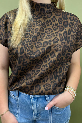Person wearing a leopard print top and blue jeans against a green background