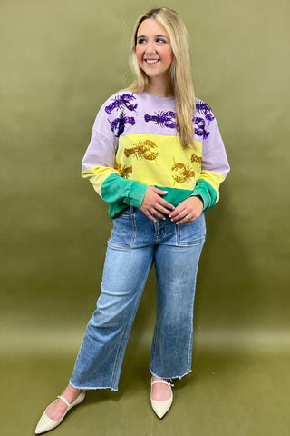 Woman wearing a colorful sweater with fish patterns and blue jeans on a green background