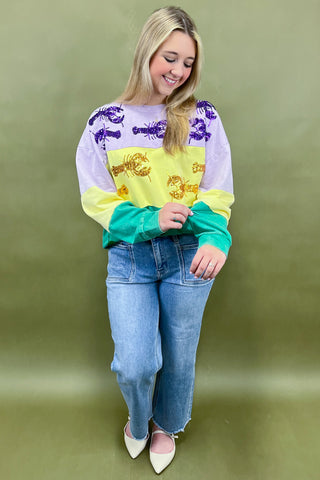 Woman wearing a colorful sweater and jeans against a green background
