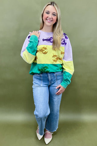Woman wearing a colorful sweater with a pattern and jeans against a green background