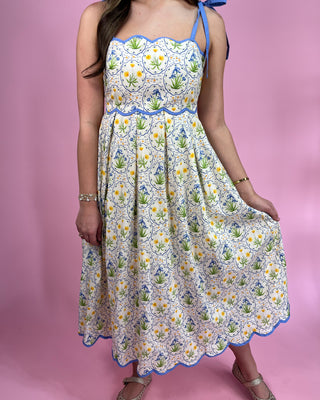 Woman wearing a floral dress with a blue trim on a pink background