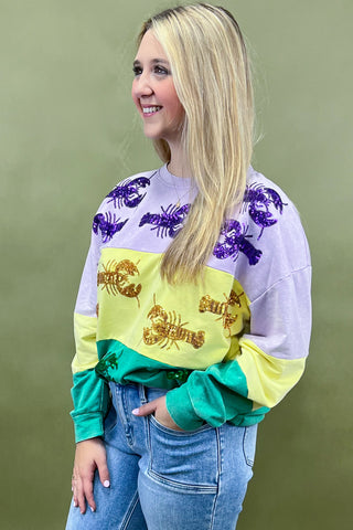 Woman wearing a colorful sweatshirt with graphic designs on a green background