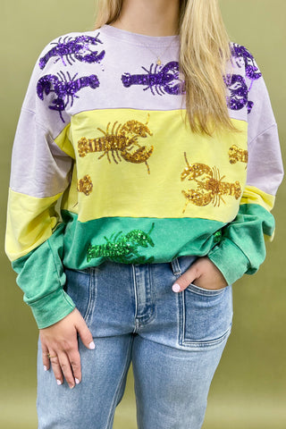 Person wearing a colorful sweatshirt with lobster designs on a green background