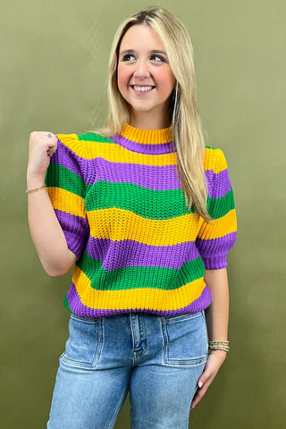 Woman wearing a colorful striped sweater against a green background