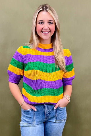 Woman wearing a colorful striped sweater against a green background