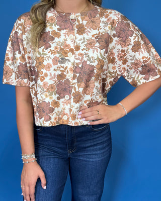 Ivory short sleeve button-front top with an allover brown, mocha, and tan floral print and relaxed fit.