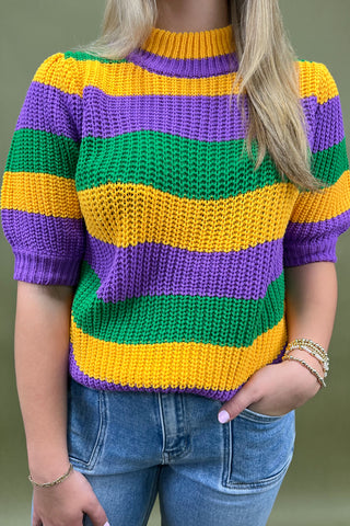 Person wearing a colorful striped sweater with green, yellow, and purple horizontal stripes.