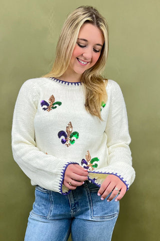 Woman wearing a white sweater with colorful designs against a green background