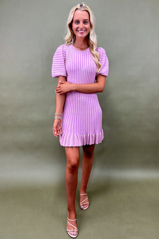 Woman wearing a purple dress against a plain background