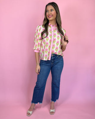 Woman wearing a floral blouse and jeans on a pink background