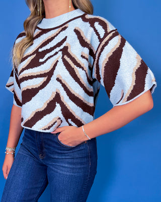 Light blue knit sweater top with bold chocolate brown and cream zebra print, crew neckline, and relaxed short sleeves
