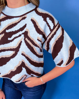 Light blue knit sweater top with bold chocolate brown and cream zebra print, crew neckline, and relaxed short sleeves