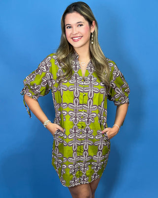 A woman modeling a short-sleeve mini dress with a green, white, and brown dragonfly pattern