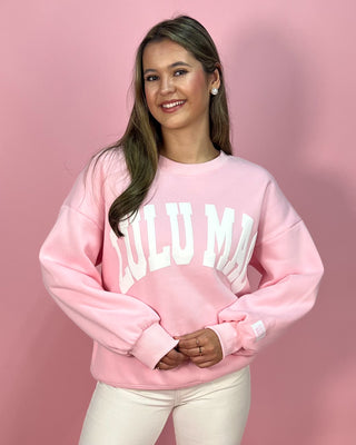 Person wearing a pink sweatshirt with text on a pink background