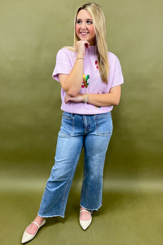 Woman wearing a pink top and blue jeans against a green background