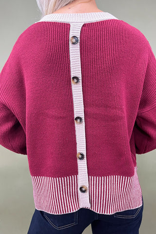 Pink cardigan with button details on a neutral background