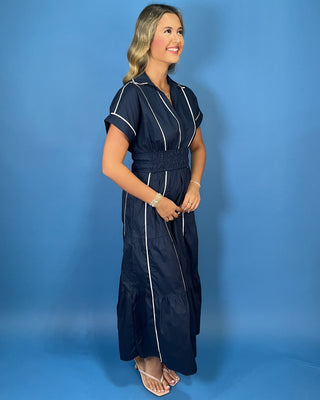 Navy midi dress with crisp white piping, a flattering V-neckline, short sleeves, smocked waist, and tiered flowy skirt.