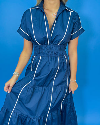 Navy midi dress with crisp white piping, a flattering V-neckline, short sleeves, smocked waist, and tiered flowy skirt.