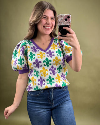 Woman taking a mirror selfie wearing a colorful patterned shirt against a plain background