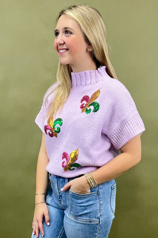Woman wearing a light purple sweater with colorful butterfly designs on a green background