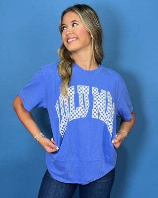 Woman modeling a blue graphic T-shirt with white checkered lettering and dark wash jeans.