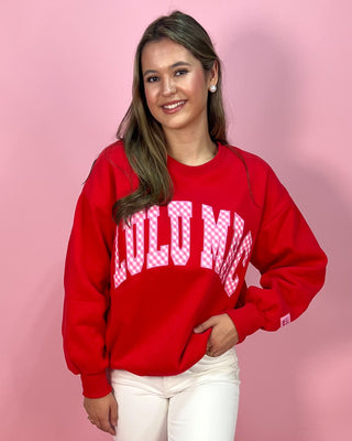 Person wearing a red sweatshirt with text on a pink background