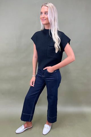 Black ribbed knit top with mock neck and chest pocket styled with dark wide leg cropped jeans and white loafers