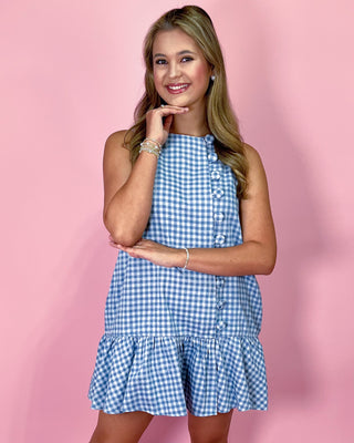 Woman wearing a blue and white checkered dress against a pink background