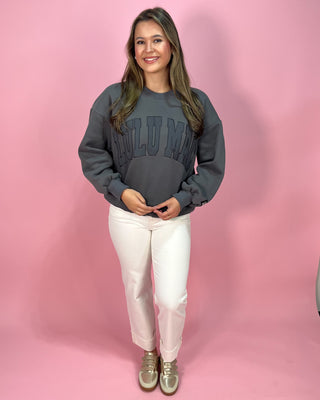 Person wearing a gray sweatshirt with  text on a pink background