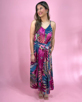 Woman wearing a colorful floral dress against a pink background