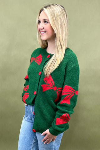 Woman wearing a green cardigan with red patterns against a beige background
