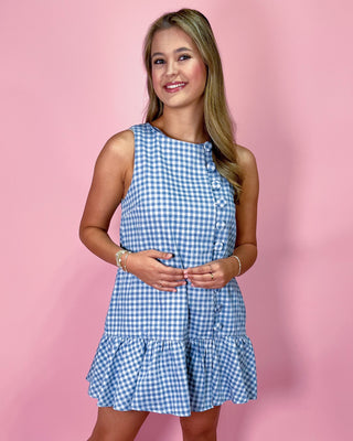 Woman wearing a blue checkered dress against a pink background