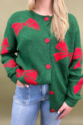 Green cardigan with red patterns worn by a person against a beige background