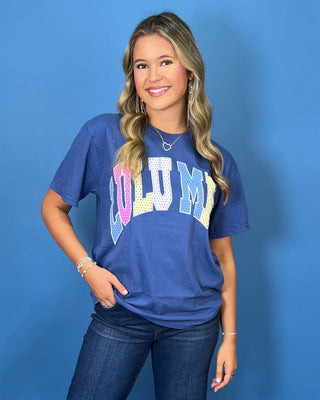 Woman modeling a navy graphic T-shirt with colorful varsity lettering, dark wash wide leg jeans, and sneakers.