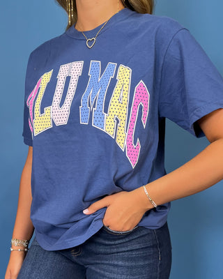Woman modeling a navy graphic T-shirt with colorful varsity lettering, dark wash wide leg jeans, and sneakers.