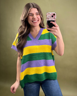 Woman wearing a colorful striped sweater taking a selfie against a green background