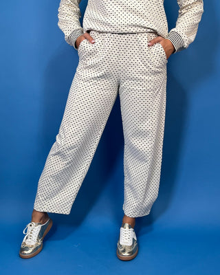 Ivory polka dot two-piece set with long sleeve pullover top, striped trim, and relaxed wide leg pants.