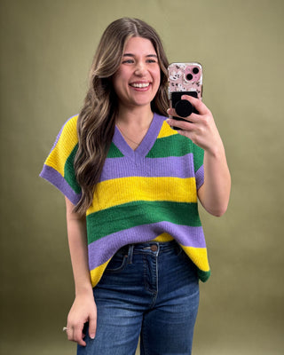 Woman wearing a colorful striped sweater taking a selfie against a green background