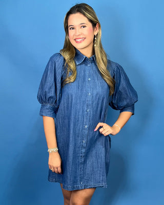 A woman modeling a blue chambray button-down shirt dress with puff sleeves