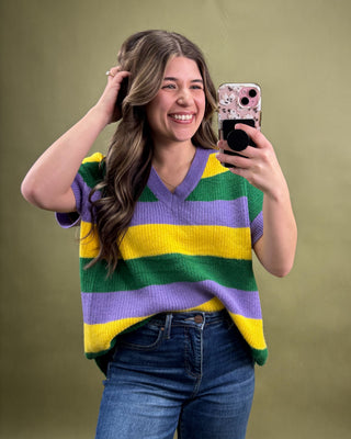 Woman wearing a colorful striped sweater taking a selfie against a green background