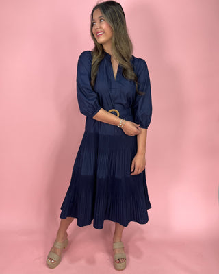 Woman wearing a navy blue dress against a pink background