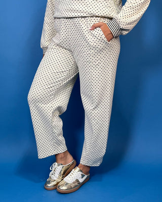 Ivory polka dot two-piece set with long sleeve pullover top, striped trim, and relaxed wide leg pants.