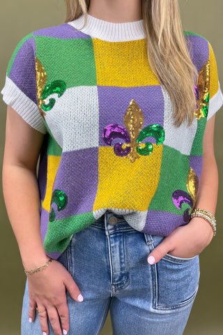 Person wearing a colorful sweater with Mardi Gras patterns and beads.