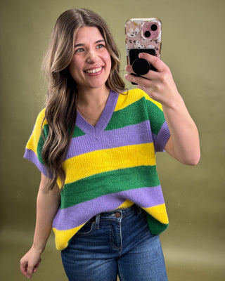 Woman wearing a colorful striped sweater taking a selfie against a green background