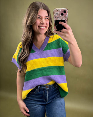 Woman taking a selfie wearing a colorful striped sweater against a green background